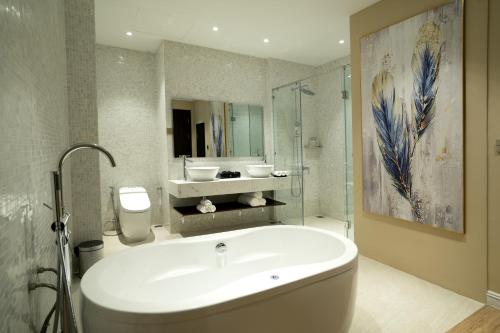 a bathroom with a tub and a sink and a mirror at Millennium Hue Hotel in Hue