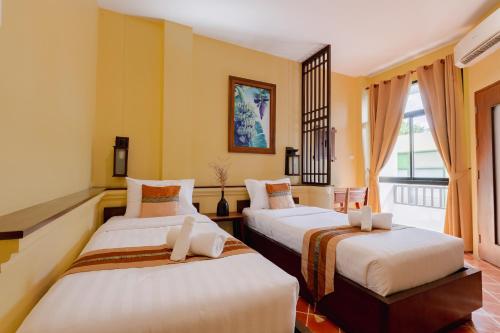 2 camas en una habitación con paredes amarillas en Huen Hug Chiang Mai, en Chiang Mai
