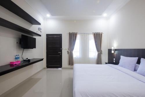 Kelayang Beach Hotel في Tanjungbinga: غرفة نوم بسرير ابيض كبير ونافذة