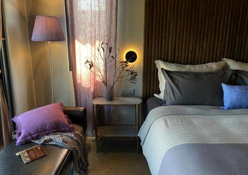 a bedroom with a bed and a chair and a table at Kaia Gallery Hotel Hoi An in Hoi An