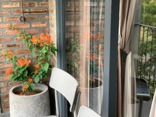 a porch with two white chairs and orange flowers at Kaia Gallery Hotel Hoi An in Hoi An