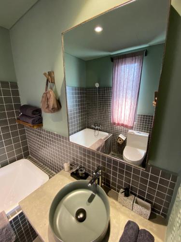 a bathroom with a sink and a tub and a mirror at Kaia Gallery Hotel Hoi An in Hoi An