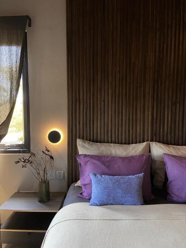 a bedroom with a large bed with purple pillows at Kaia Gallery Hotel Hoi An in Hoi An