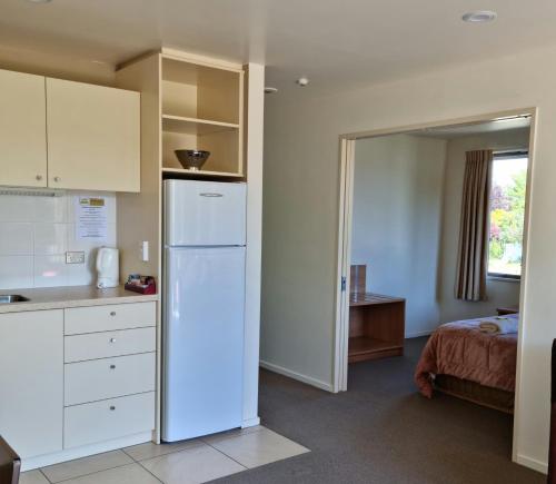 eine Küche mit einem Kühlschrank und ein Bett in einem Zimmer in der Unterkunft Methven Motel & Apartments in Methven
