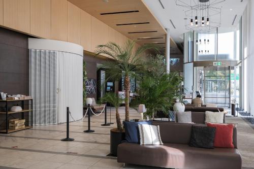a lobby with a couch and palm trees in it at Hotel JAL City Haneda Tokyo in Tokyo