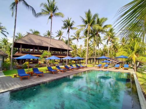 a pool at the resort with chairs and umbrellas at The Kirana Tembok in Tejakula