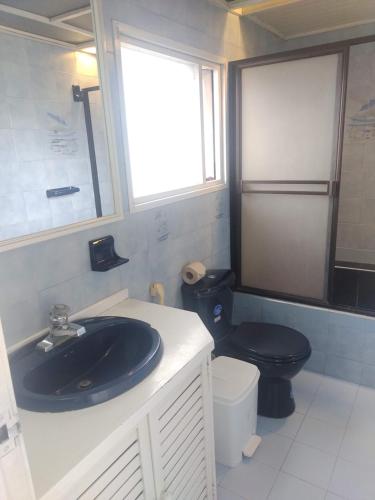 baño con aseo negro y lavamanos en Bioelemental hotel sustentable Bogotá, en Bogotá