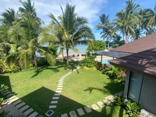 a garden with palm trees and a walkway next to a house at Amila Dive Beach Resort in Sipalay