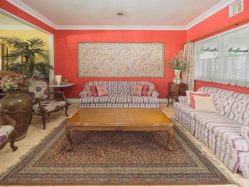 a living room with red walls with couches and a table at Kulem Gempol in Bandung
