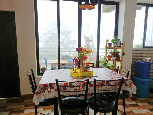 a dining room table with chairs and a table with flowers on it at Wonder Hill Parivaar homestay in Darjeeling