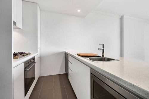 uma cozinha branca com um lavatório e uma bancada em Panoramic City View 3bed2bath condo Wi-Fi Parking em Sydney