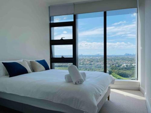 um quarto com uma cama branca e uma grande janela em Panoramic City View 3bed2bath condo Wi-Fi Parking em Sydney