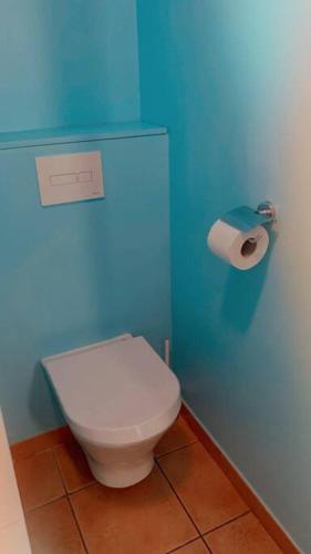 a bathroom with a white toilet and a blue wall at Studio Premium Vue Mer, Plage in Sainte-Luce