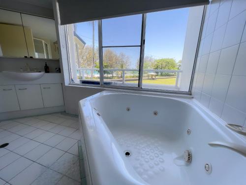 baño con bañera blanca y ventana en 6 Ulysses - Spacious Beachfront Apartment en Mission Beach