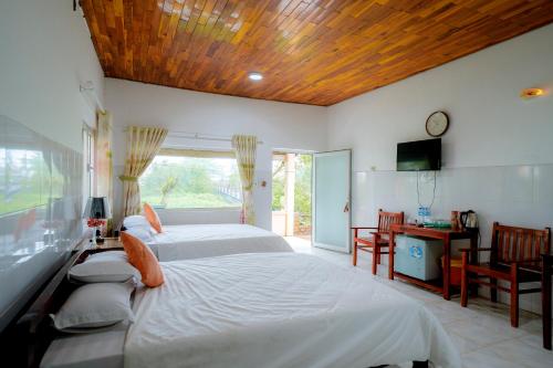 sypialnia z 2 łóżkami, biurkiem i oknem w obiekcie Thai Tan Tien Hotel w Duong Dong