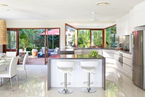 a kitchen with a bar with white stools in it at 15 Nairana Rest Noosa Heads in Noosa Heads
