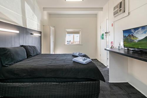 a bedroom with a bed with a television on a wall at Tinman Roadhouse in Napperby