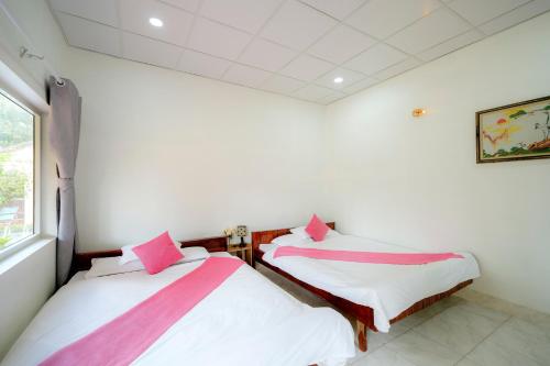 two beds in a room with white walls and a window at Thai Tan Tien Hotel in Phu Quoc