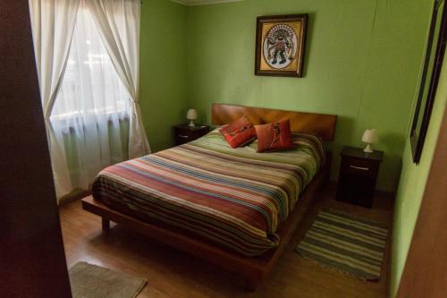 sypialnia z łóżkiem z zielonymi ścianami i oknem w obiekcie Cabañas Jazmín w mieście Palmilla