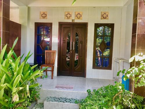 a house with a wooden door and a chair at Wahyu Homestay 1 in Nusa Lembongan