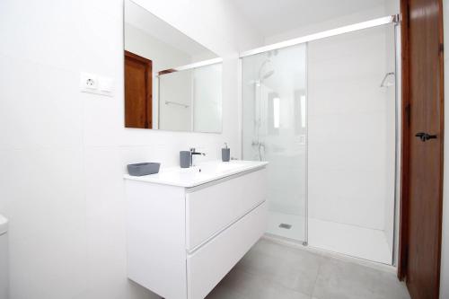 uma casa de banho branca com um lavatório e um chuveiro em Del Parque Flats Villa Sauce em Chilches