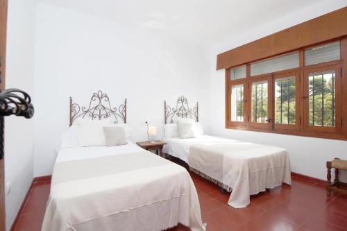 2 camas en una habitación con paredes y ventanas blancas en Del Parque Flats Villa Sauce, en Chilches