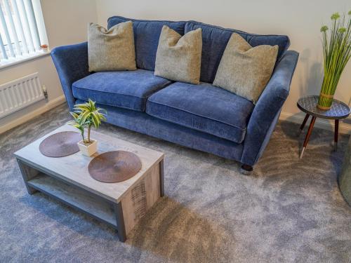 a living room with a blue couch and a coffee table at Modern 3-Bed Home with Garden & Free Parking - Pass the Keys in Nottingham