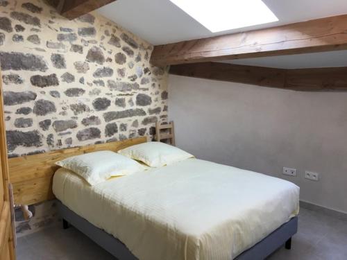 a bed in a room with a stone wall at appartement de l'église et du château 2 à 15 personnes in Avène