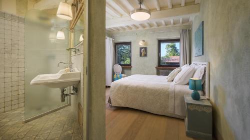 a bedroom with a bed and a sink and a bathroom at LA DAMA DEL BOSCO 8&3, Emma Villas in Capriglia