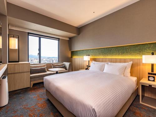 a hotel room with a bed and a large window at THE BLOSSOM KUMAMOTO in Kumamoto