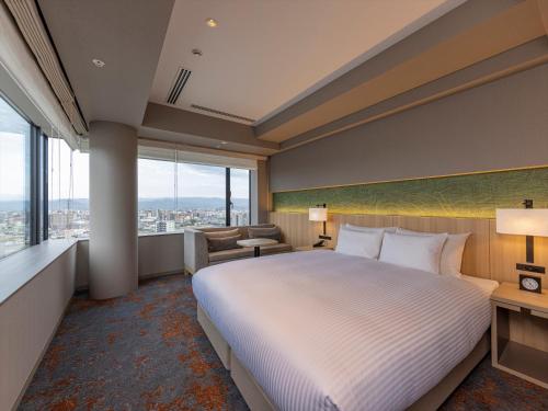 a hotel room with a bed and a large window at THE BLOSSOM KUMAMOTO in Kumamoto