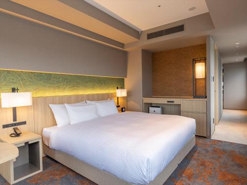 a bedroom with a large white bed and a desk at THE BLOSSOM KUMAMOTO in Kumamoto