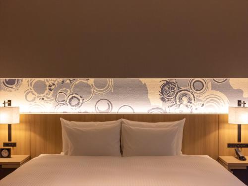 a bedroom with a large white bed with two lamps at THE BLOSSOM KUMAMOTO in Kumamoto
