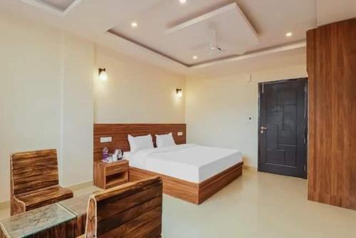 a bedroom with a white bed and a black door at Hotel Rabbit Hut in Dehradun