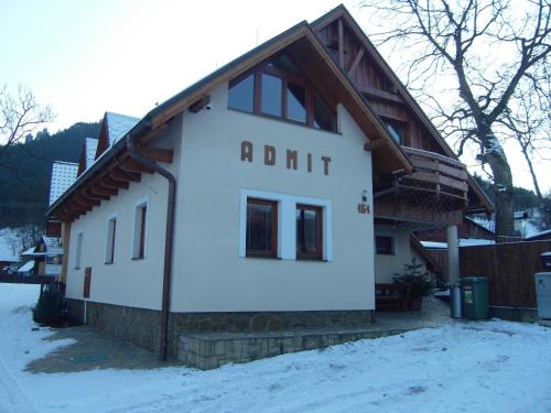 a white building with a wooden roof in the snow at Penzión Admit in Terchová