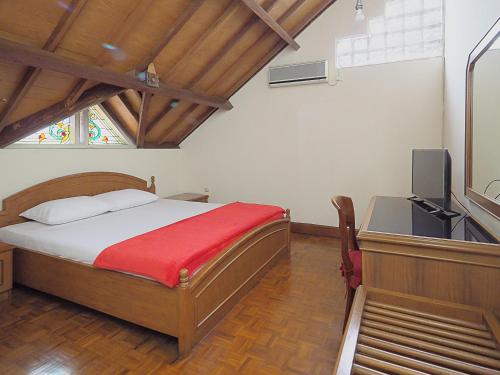 a bedroom with a bed and a desk with a television at Kulem Gempol in Bandung