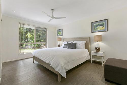 a white bedroom with a bed and a window at 21 David Street Noosa Heads in Noosa Heads