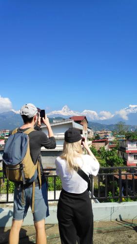 un homme prenant une photo d'une femme avec une caméra dans l'établissement Hotel Mountain View - Lakeside Pokhara, à Pokhara
