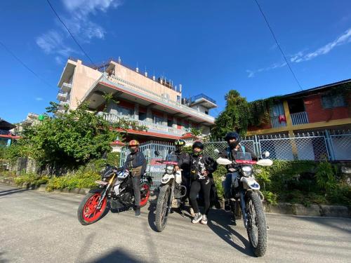 Hotel Mountain View - Lakeside Pokhara في بوخارا: ثلاثة أشخاص على دراجات نارية متوقفة أمام مبنى