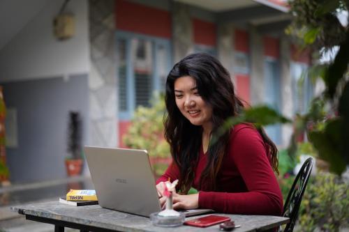 een vrouw aan een tafel met een laptop bij Hotel Mountain View - Lakeside Pokhara in Pokhara
