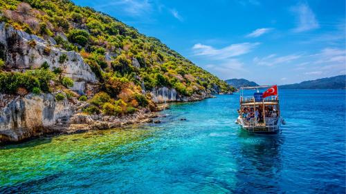 un bateau sur l'eau à côté d'une montagne dans l'établissement BİLGİNER APART, à Demre