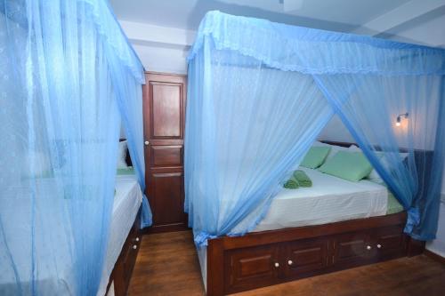 a bedroom with a bed with blue drapes at SEVENTY SEVEN GALLE in Galle
