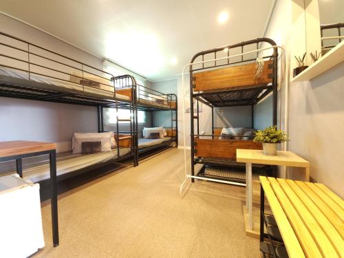 a room with three bunk beds and a bench at OYO Hostel Dongdaemun1 in Seoul
