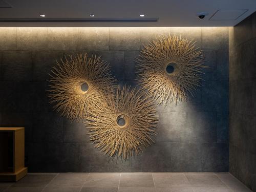 a wall with three metal flowers on it at THE BLOSSOM KUMAMOTO in Kumamoto