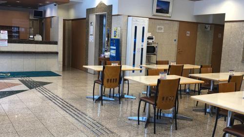 a cafeteria with tables and chairs and a kitchen at Toyoko Inn Osaka Temmabashi Otemae in Osaka