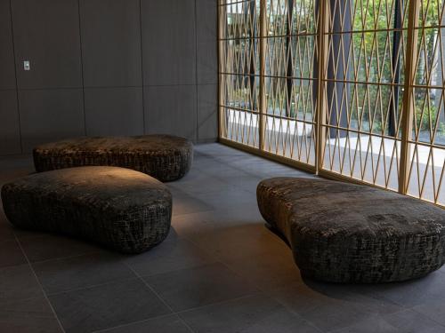 two ottomans and two stools in a room with windows at THE BLOSSOM KUMAMOTO in Kumamoto