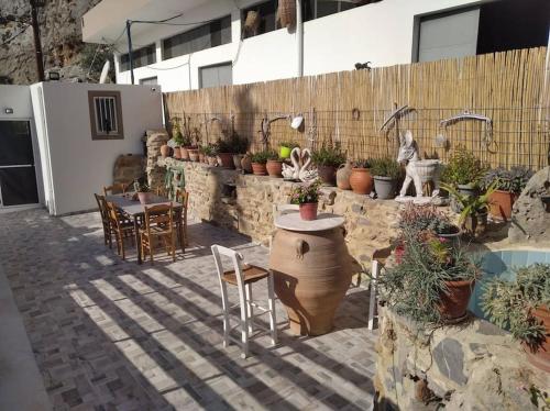 a patio with a table and chairs and potted plants at MARINOS House WANDERN&ENTSPANNEN am Fusse des Psiloritis in Kamárai