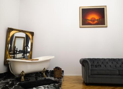 a bathroom with a tub and a mirror and a couch at Mansion Josephina in Cluj-Napoca