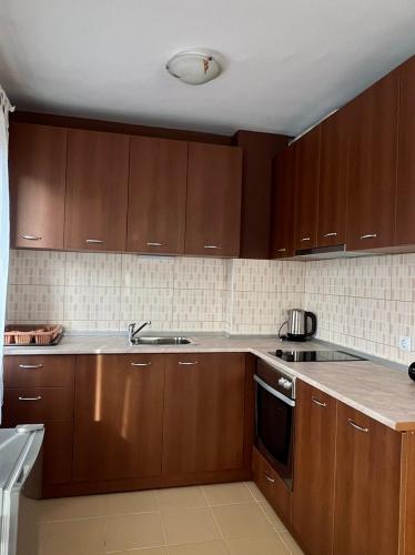 a kitchen with wooden cabinets and a sink at Prime Apartments in Bansko