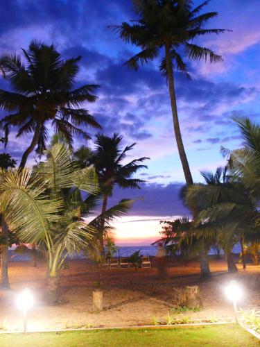 a group of palm trees on a beach at night at Marari SeaLap Beach Villas in Mararikulam